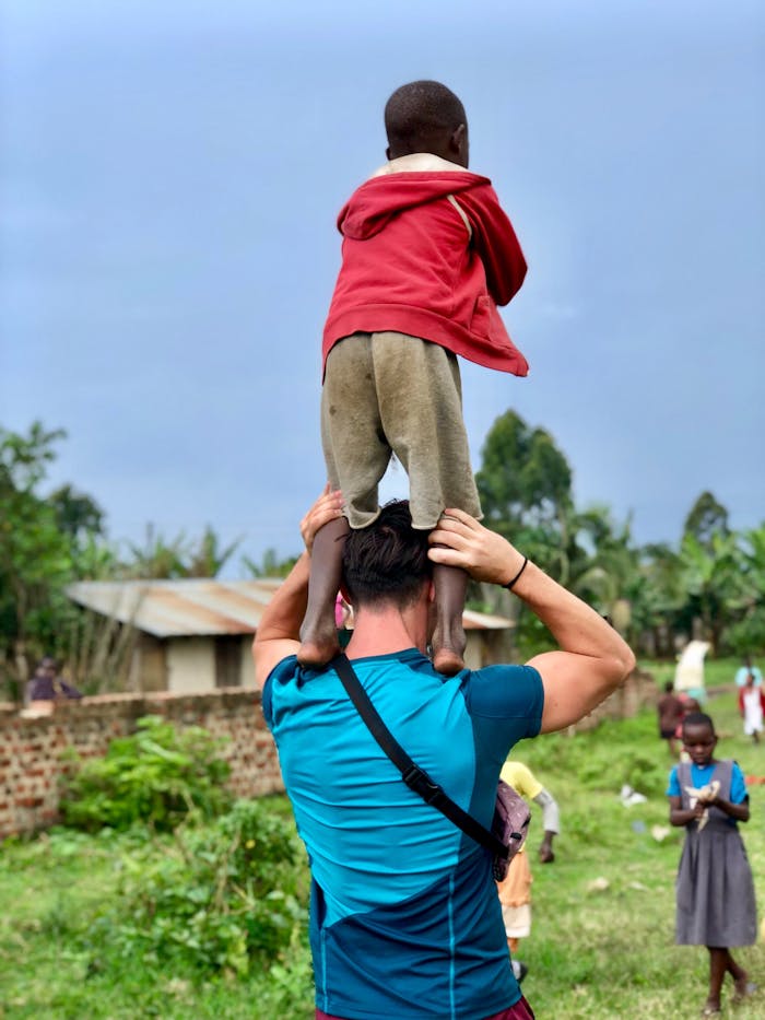 A man carries a child on his shoulders in a village in Fort Portal, Uganda.