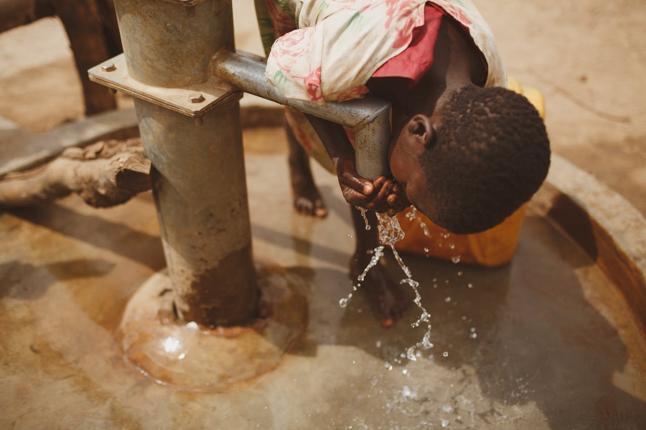 A girl bends to drink clean water from a well in Kitgum, Northern Uganda.